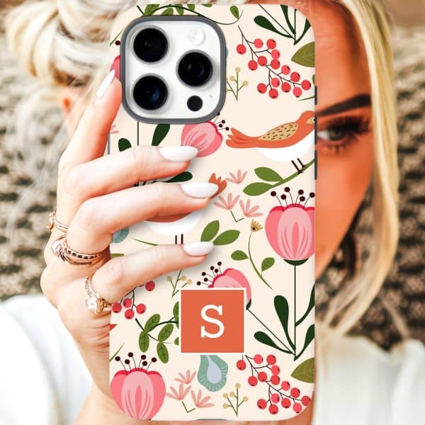 A Woman'S Hand Holding Up An Iphone Case With A Floral And Bird Pattern, And The Initial S In A Coral Square.
