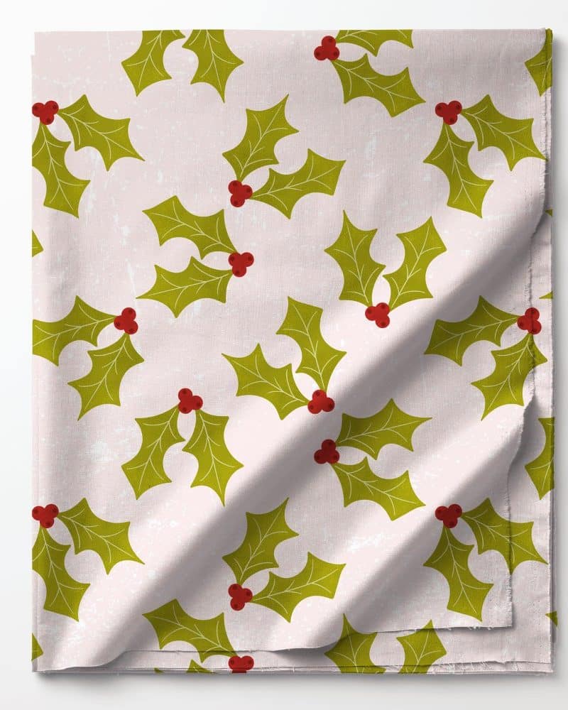 Pink fabric with a repeating pattern of green holly leaves and red berries.