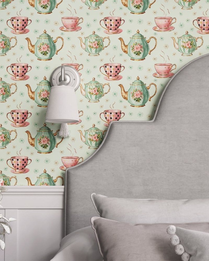 A light green wall with a repeating pattern of teacups and teapots. A gray headboard partially obscures the wallpaper.