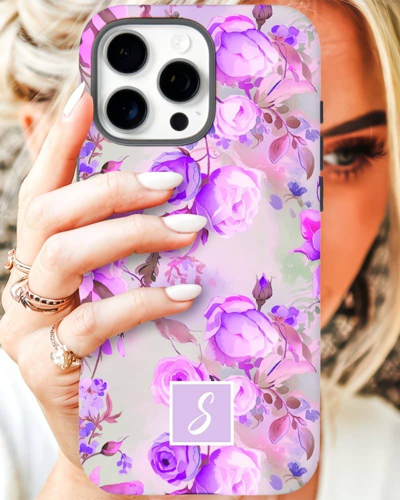 A woman's hand holding a purple floral iPhone case with a monogram.