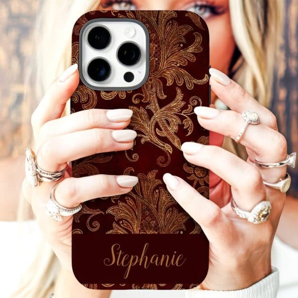 Close-Up Of Hands Holding A Red Phone Case With Gold Ornate Pattern And The Name Stephanie.