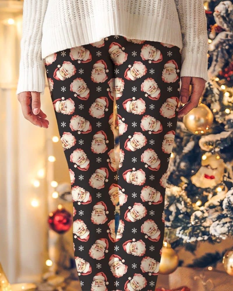 Black leggings with a repeating pattern of vintage Santa Claus faces and snowflakes.