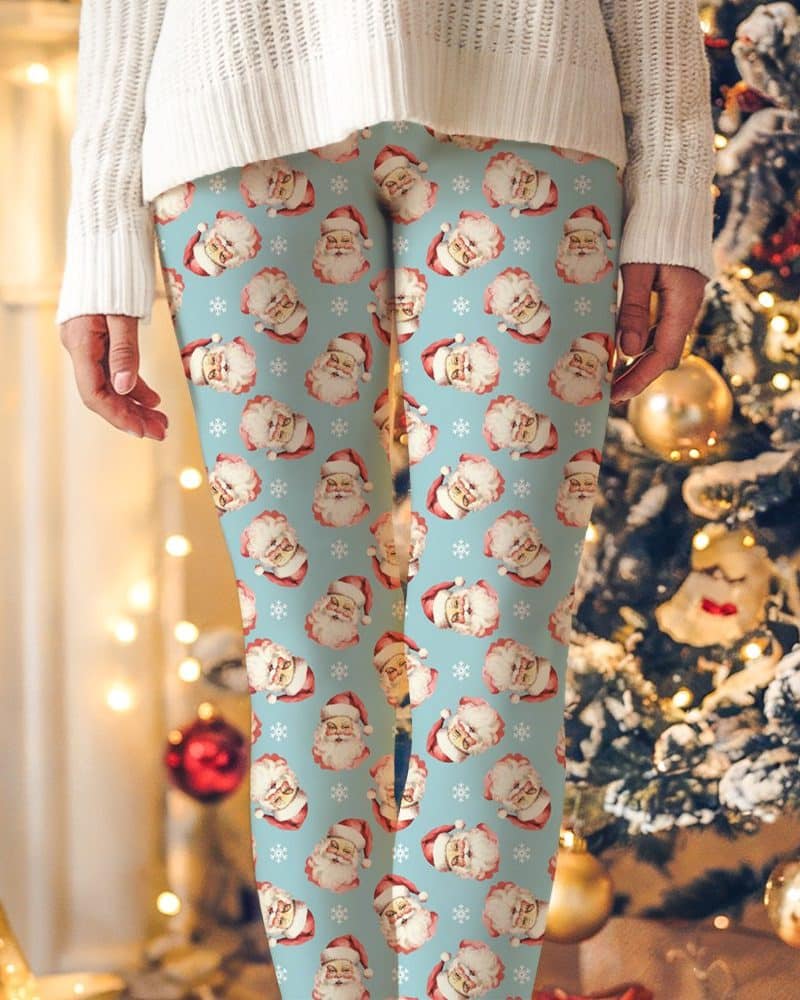 Light blue leggings with a repeating pattern of vintage Santa Claus faces and snowflakes.