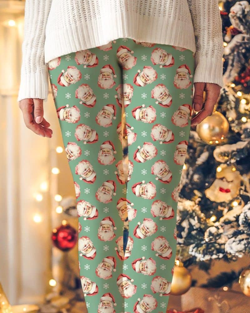 Green leggings with a repeating pattern of vintage Santa Claus faces and snowflakes.