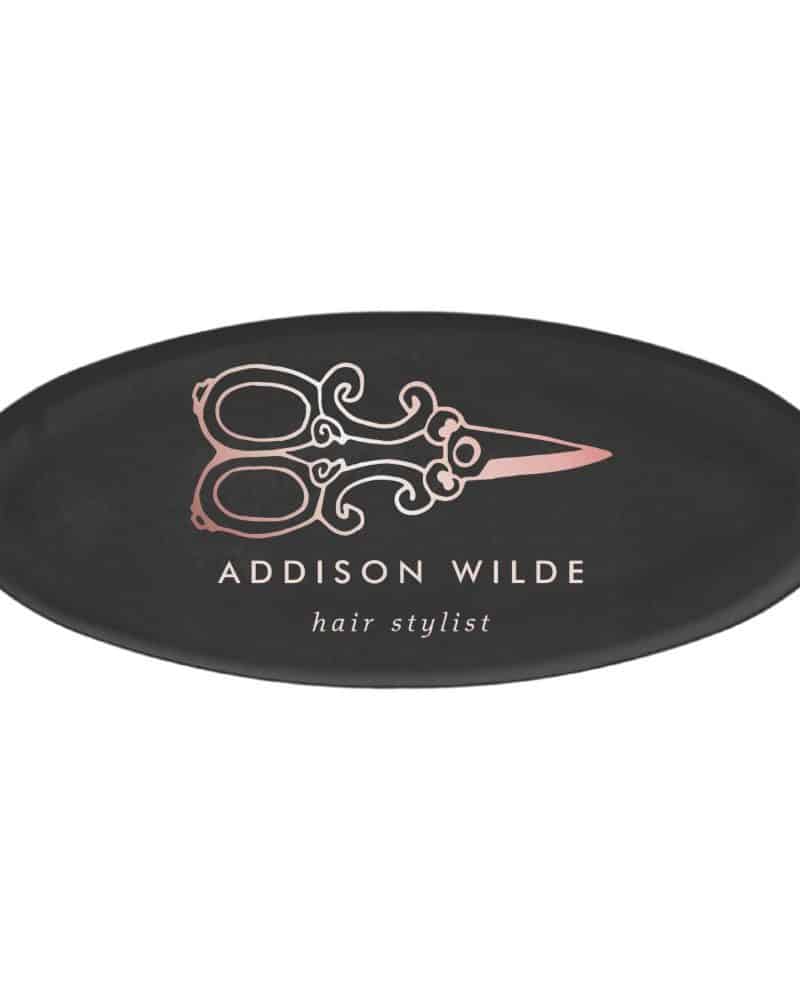 Black oval logo with a rose gold pair of scissors and the text Addison Wilde hair stylist.