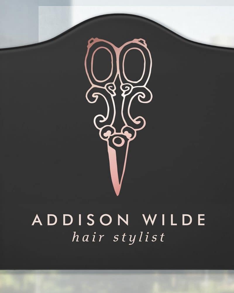 Black rectangular sign with rounded top, featuring a rose gold pair of ornate scissors and the text Addison Wilde hair stylist.
