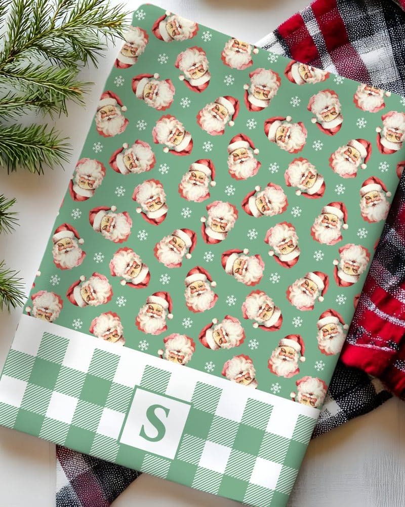 Green and white gingham wrapping paper featuring a repeating pattern of vintage Santa Claus illustrations. A monogrammed initial S is in the lower section.