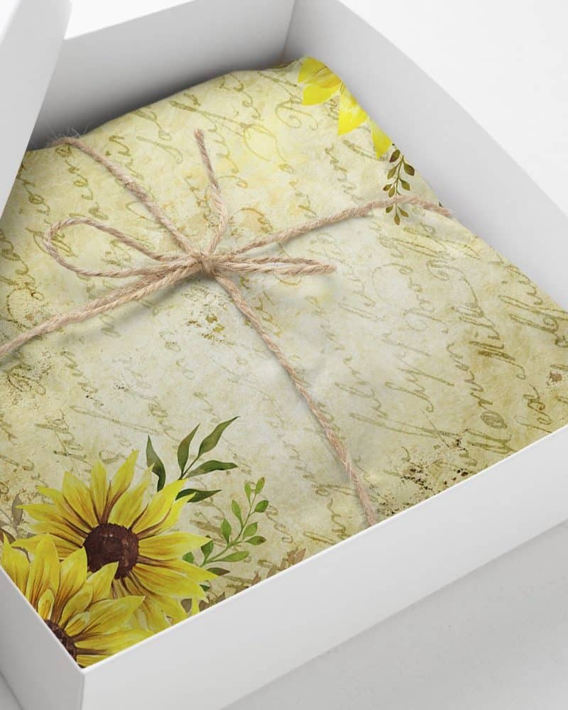 Gift box containing a package wrapped in twine, featuring a sunflower and antique-style floral design.