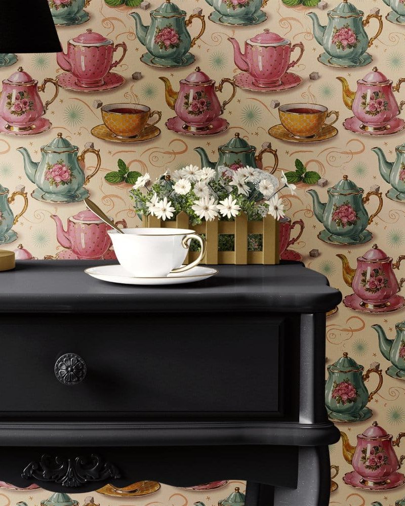 A teacup and saucer sit on a dark dresser in front of wallpaper featuring a repeating pattern of teapots and teacups.