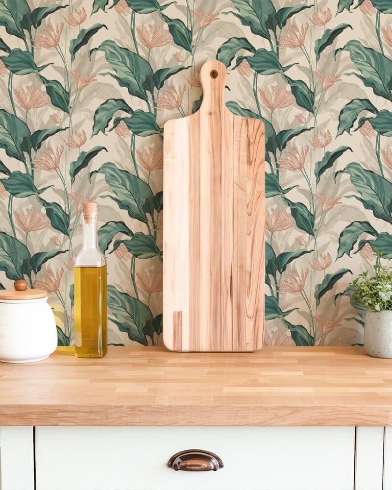 A wooden cutting board rests against a wall covered in teal and peach floral wallpaper.