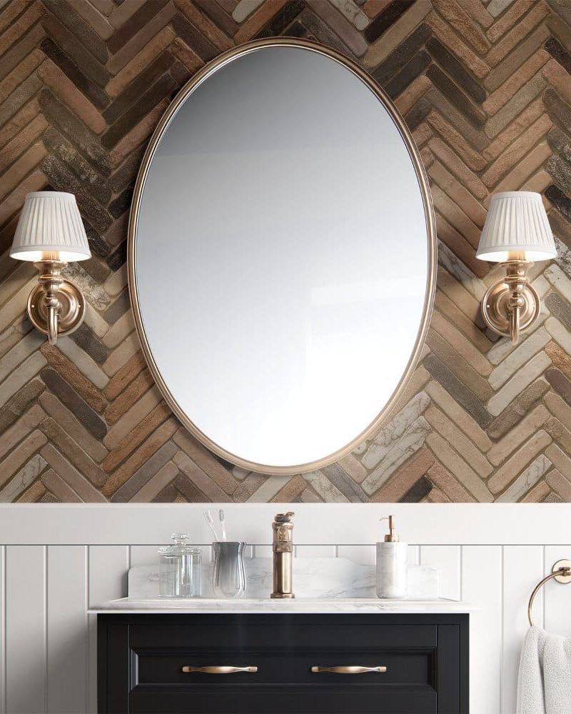 Oval mirror with gold frame above a bathroom vanity.