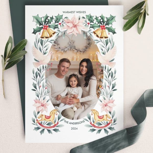 Christmas Card Featuring A Family Portrait Framed By A Watercolor Floral Design With Doves, Bells, And Rocking Horses.