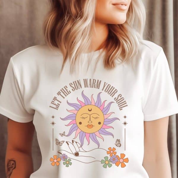 Woman Wearing A White T-Shirt Featuring A Stylized Sun Design With The Text Let The Sun Warm Your Soul.