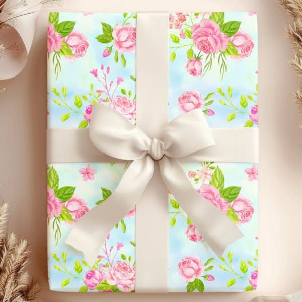 A Gift Wrapped In Light Blue Paper With A Pink Rose Pattern And Tied With A Large Cream-Colored Bow.