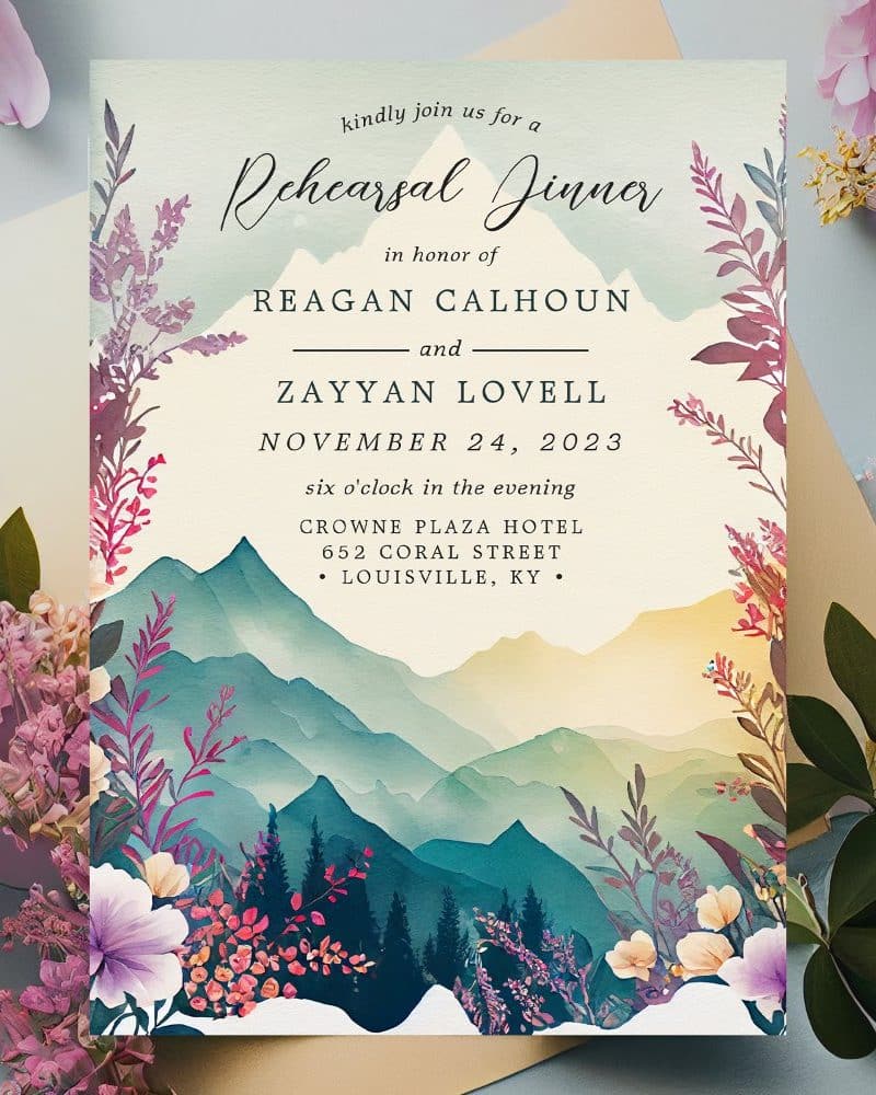 Rehearsal dinner invitation for Reagan Calhoun and Zayyan Lovell, November 24, 2023, at the Crowne Plaza Hotel in Louisville, Kentucky. The invitation features a watercolor mountain landscape with floral accents.