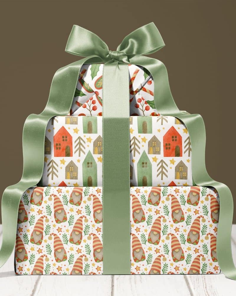 A stack of three Christmas presents, wrapped in festive paper and tied with a sage green ribbon.