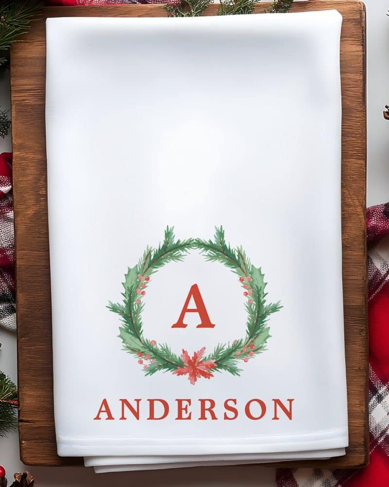 White tea towel with a red A in a Christmas wreath and the last name Anderson printed on it.
