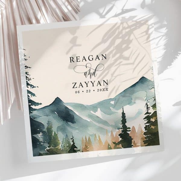Wedding Invitation Featuring A Watercolor Painting Of Mountains And Trees. The Names Reagan And Zayyan And The Date Are Printed Above The Image.