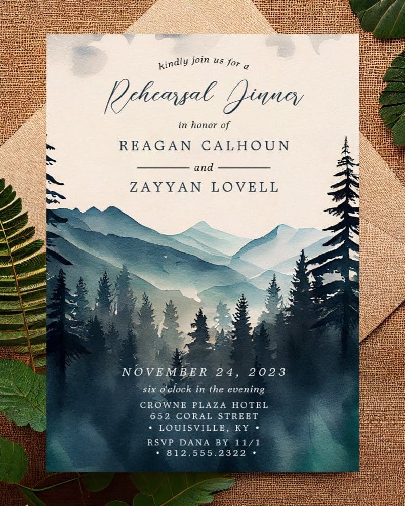 A watercolor painting of a mountain range and forest, forming the background of a rehearsal dinner invitation for Reagan Calhoun and Zayyan Lovell.