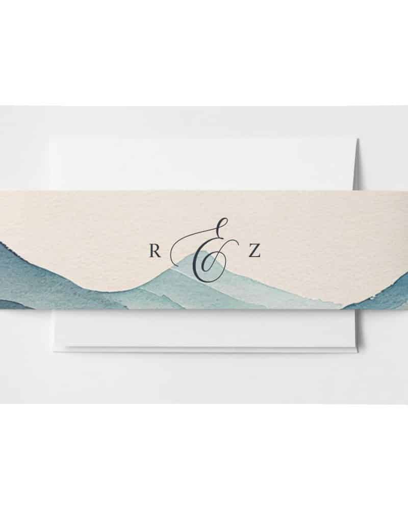 Wedding invitation with a watercolor mountain range design and monogram.