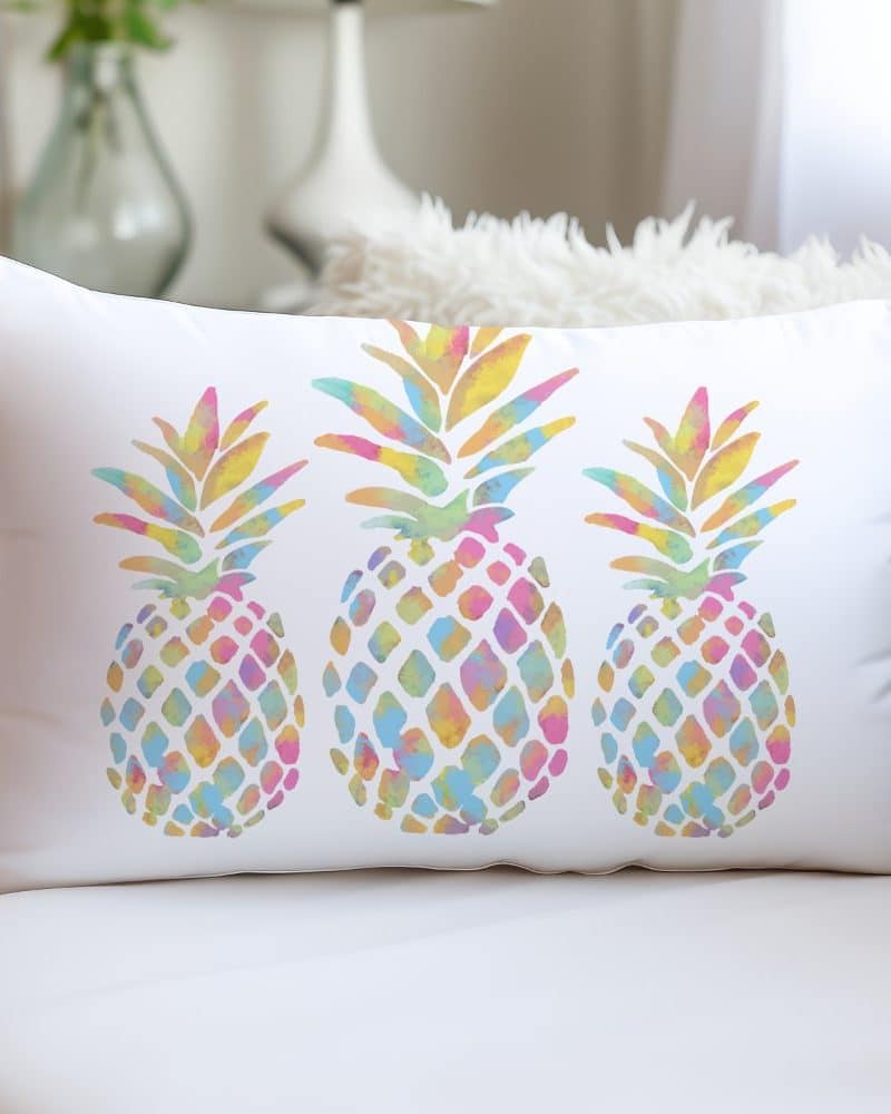 White rectangular pillow with three pastel watercolor pineapples.