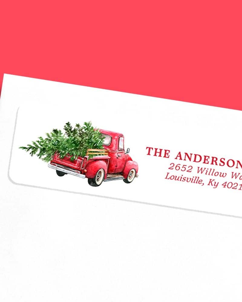 Red truck carrying a Christmas tree on a return address label.