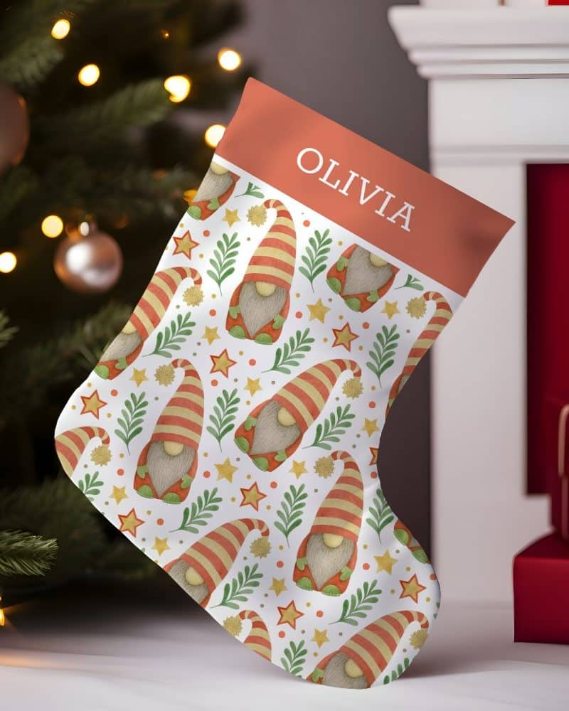 Personalized Christmas stocking with a repeating pattern of gnomes, stars, and greenery. The name Olivia is on the cuff.