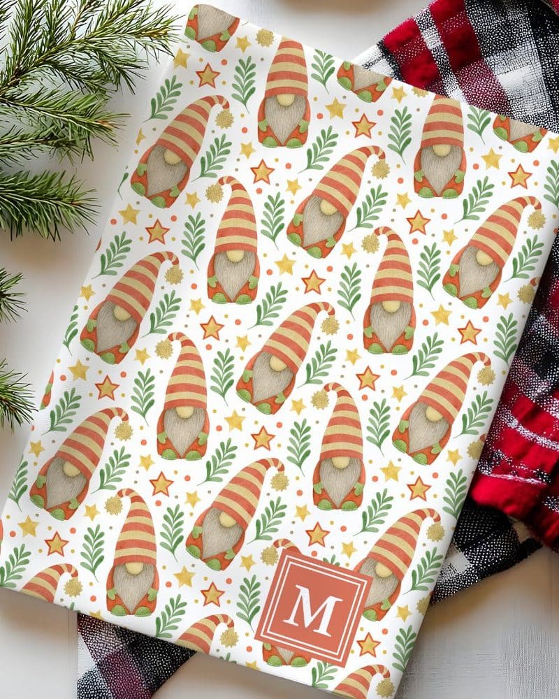 Wrapping paper featuring a repeating pattern of Christmas gnomes, stars, and greenery, personalized with the initial M.