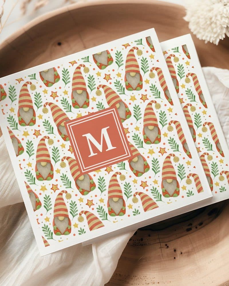 Two cards with a repeating pattern of gnomes, stars, and greenery; a monogram is centered on the top card.
