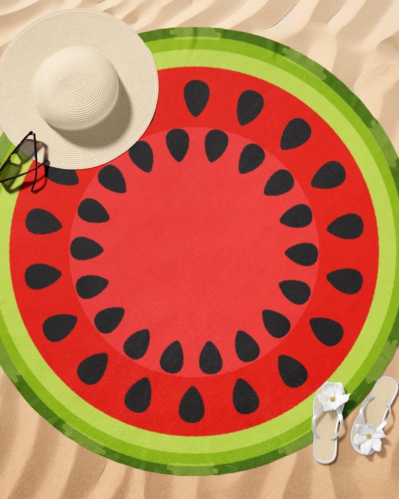Round watermelon-patterned beach towel on sand.