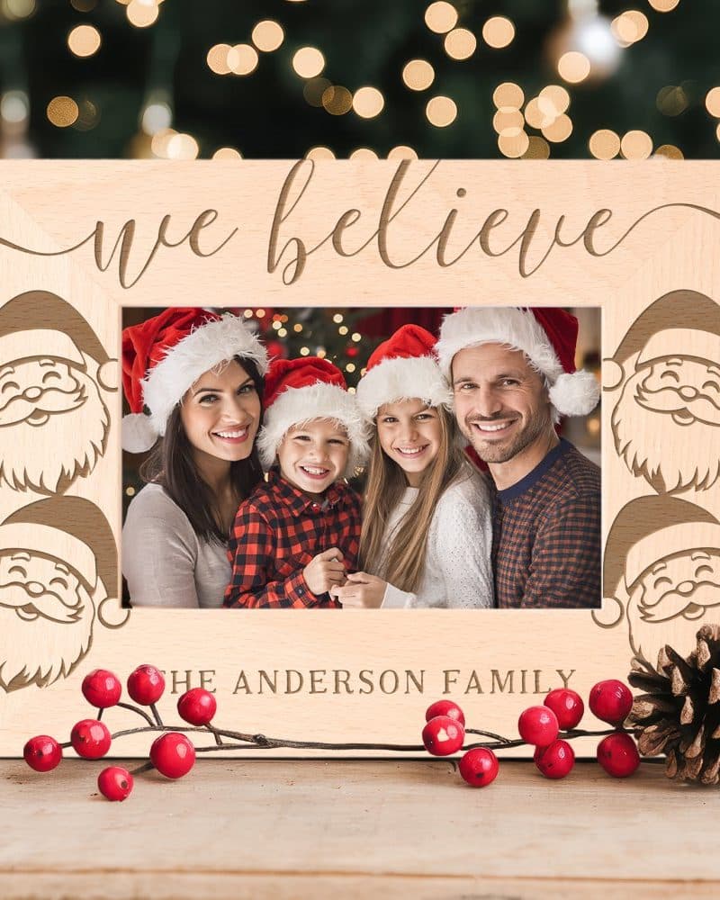 Wooden Christmas photo frame with Santa faces and the words We Believe. A family photo is inside.