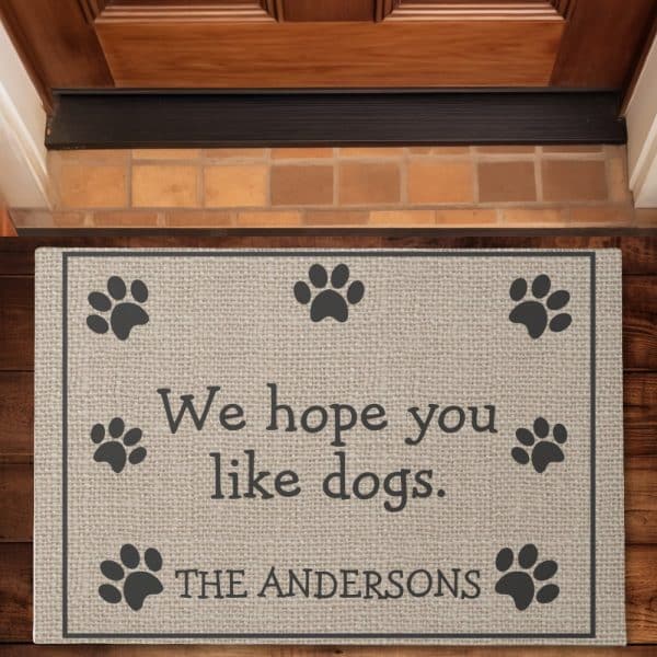 Beige Doormat With The Message We Hope You Like Dogs And The Family Name The Andersons, Surrounded By Paw Prints.