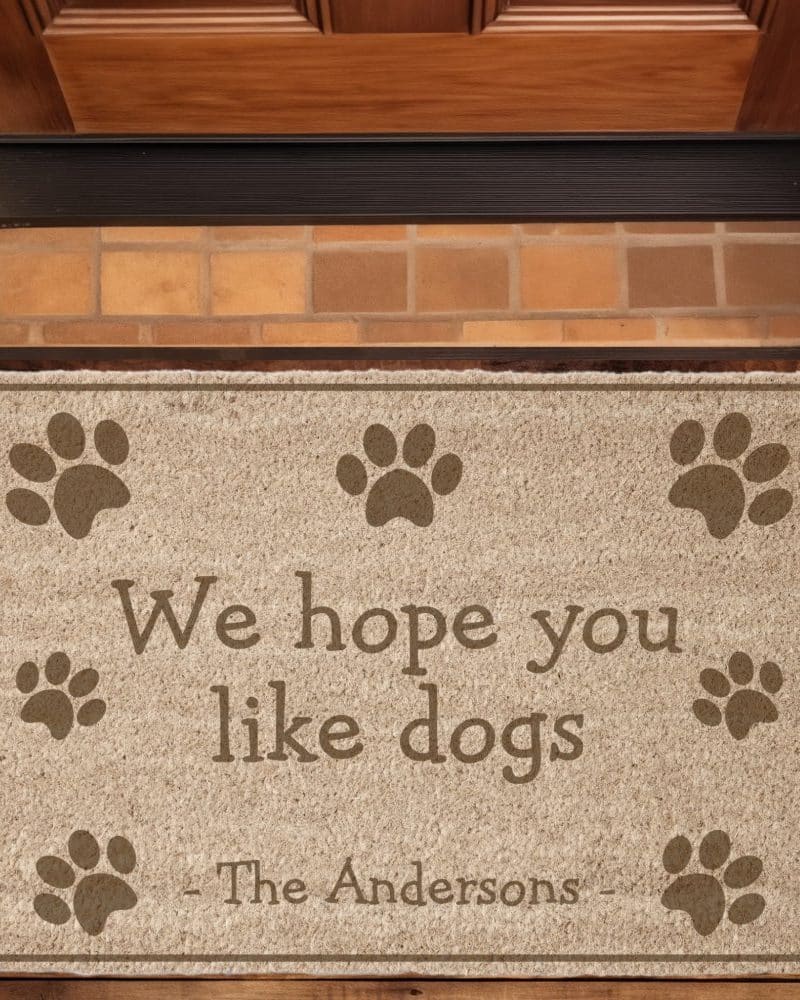 Tan doormat with paw prints and the text We hope you like dogs, The Andersons.