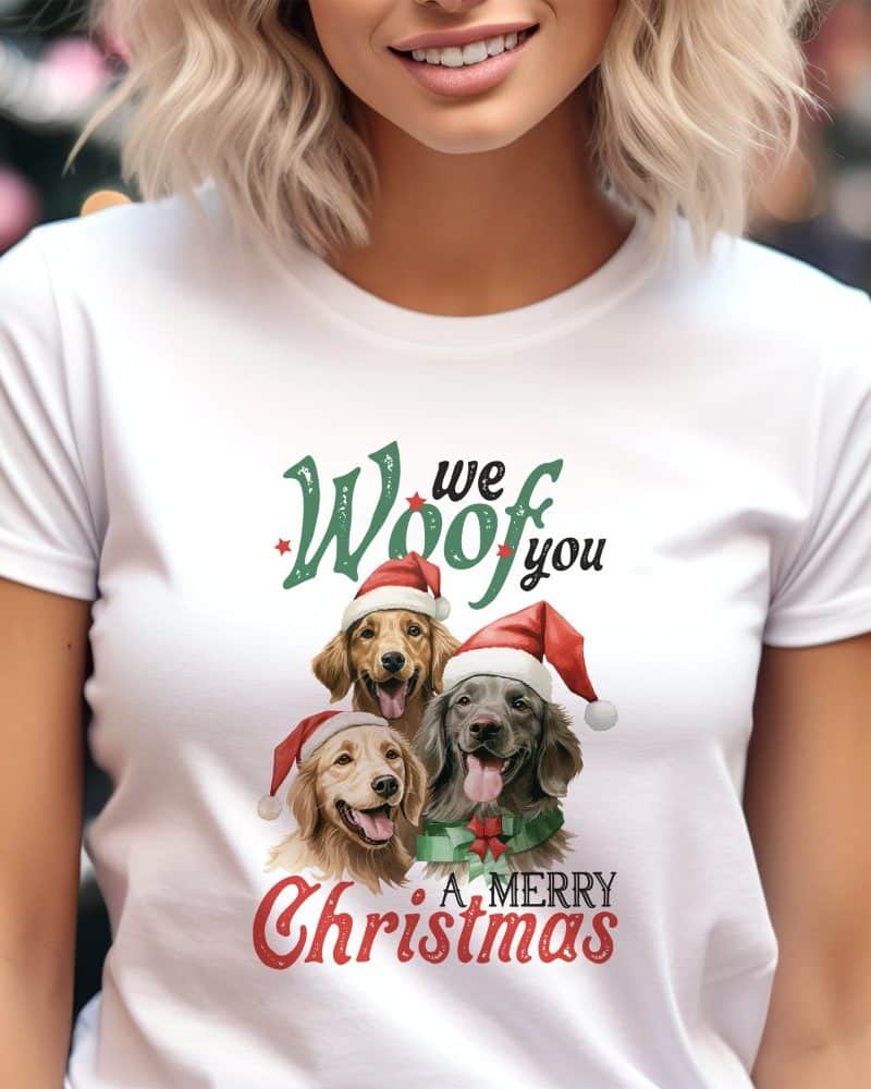 White t-shirt with a Christmas design featuring three dogs wearing Santa hats and the text We Woof You A Merry Christmas.