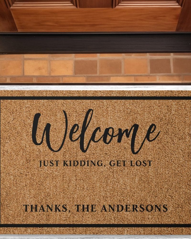 Tan welcome mat with black border and text that says Welcome, Just Kidding, Get Lost, and Thanks, The Andersons.