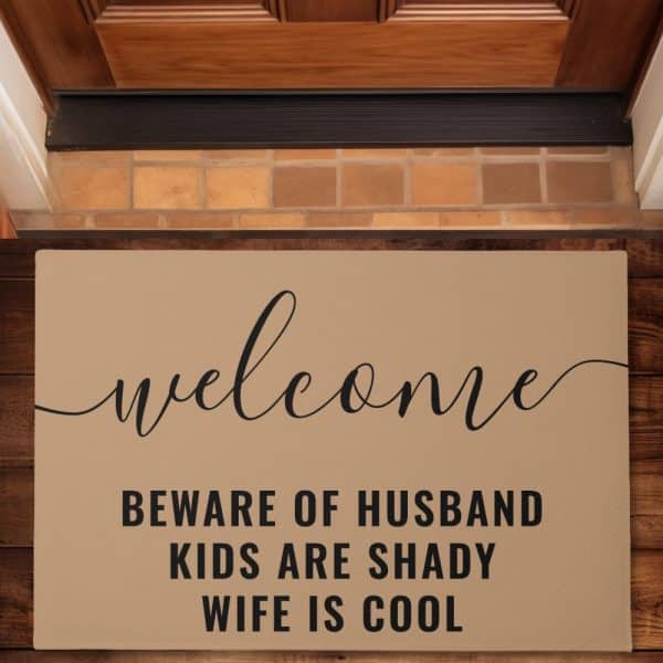 Tan Welcome Mat With The Words Welcome, Beware Of Husband, Kids Are Shady, Wife Is Cool.