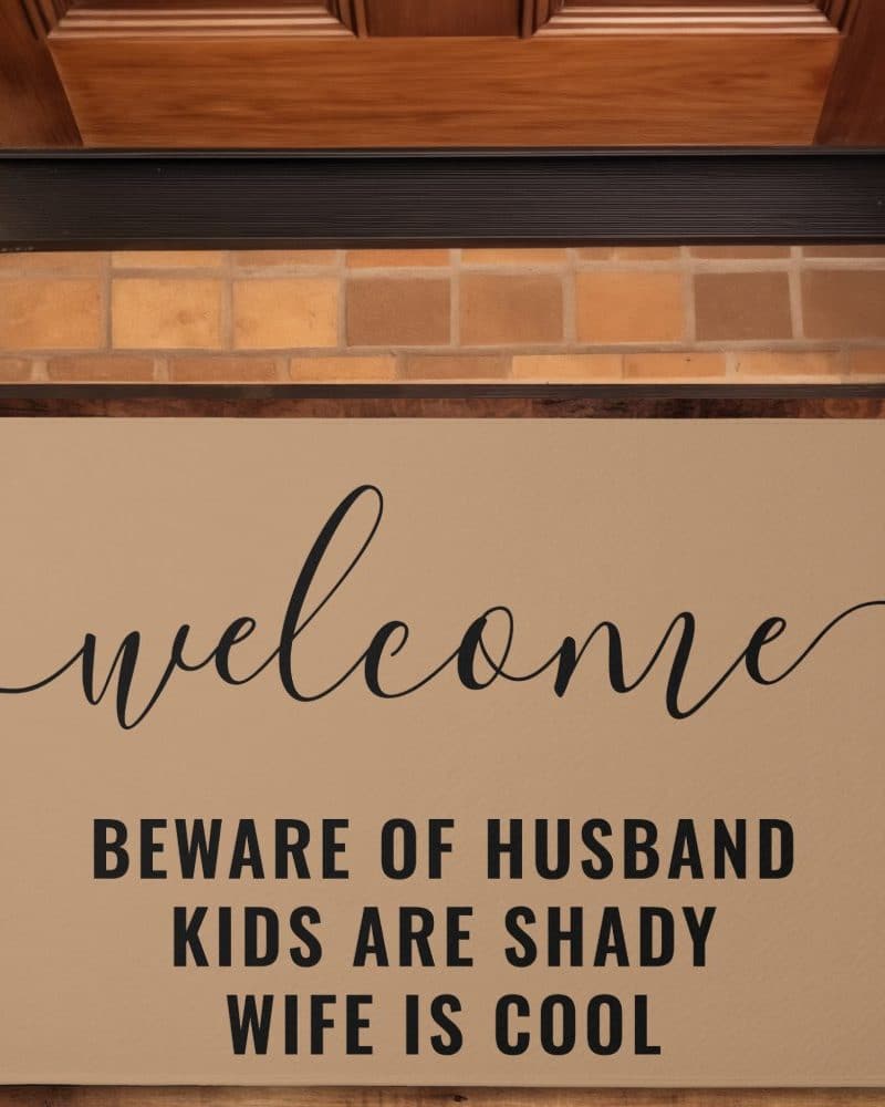 Tan welcome mat with the words Welcome, Beware of Husband, Kids are Shady, Wife is Cool.
