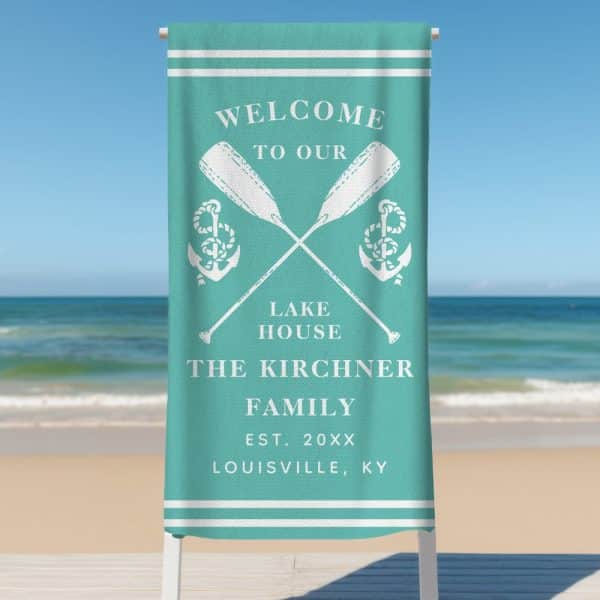 Teal Beach Towel With A Welcome Message, Crossed Oars And Anchors, And The Kirchner Family Name.
