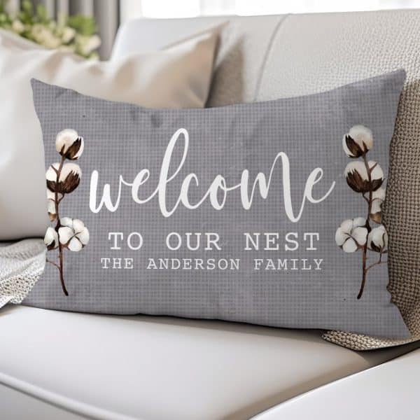 Gray Welcome Pillow With Cotton Branch Designs And The Text Welcome To Our Nest, The Anderson Family.
