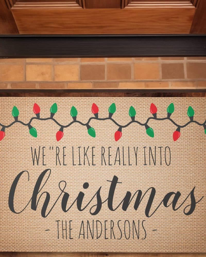 A burlap Christmas doormat with a string of lights and the text We're like really into Christmas - The Andersons.