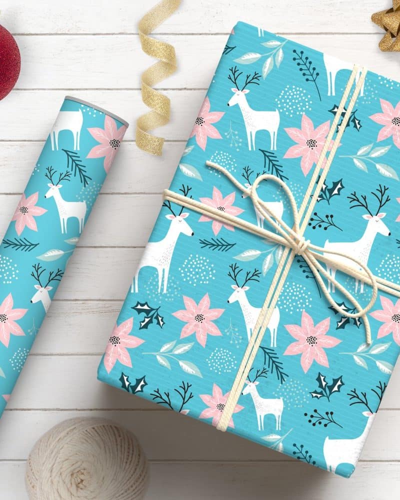 A light blue gift wrapped with a pattern of white reindeer and pink poinsettias.