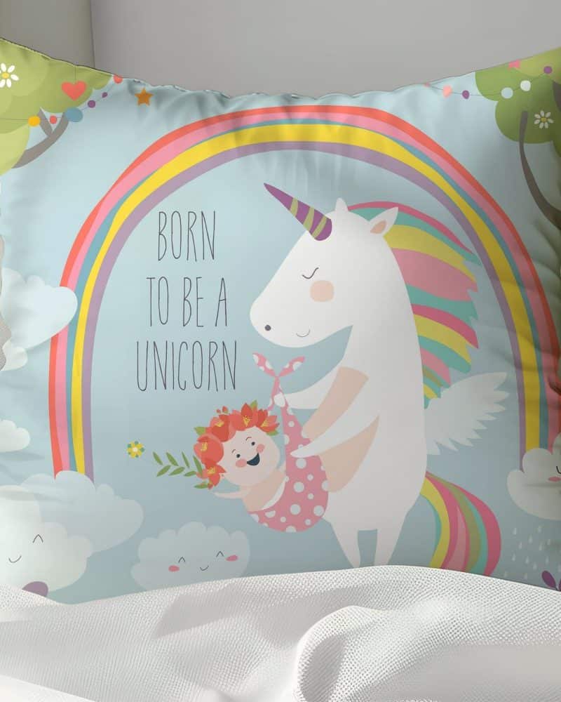 A light blue pillow featuring a unicorn holding a baby, with a rainbow and the text Born to be a Unicorn.