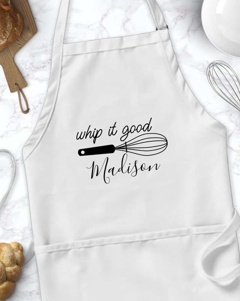White apron with the text Whip it good and Madison, along with a whisk graphic.