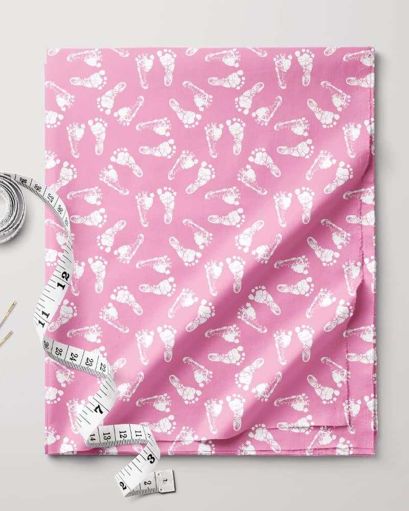 Pink fabric with a repeating pattern of white baby footprints.