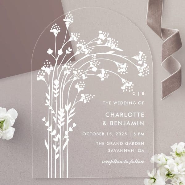Clear Acrylic Wedding Invitation With White Floral Design And Wedding Details.