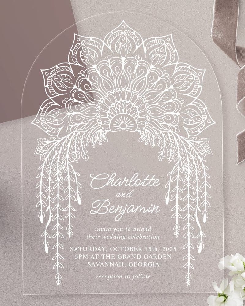 Arch-shaped clear acrylic wedding invitation with white mandala and floral designs, announcing Charlotte and Benjamin's wedding.