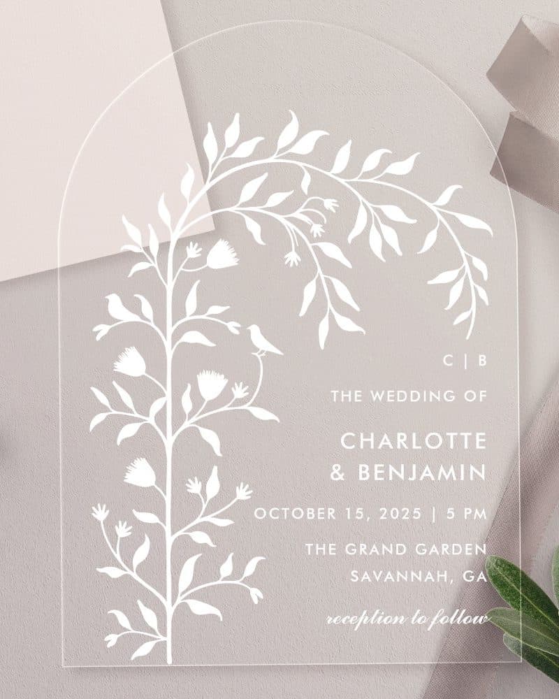 Clear acrylic wedding invitation with floral design and wedding details.