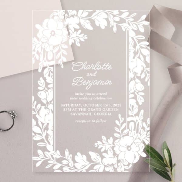 Clear Acrylic Wedding Invitation With White Floral Border And Couple'S Names.