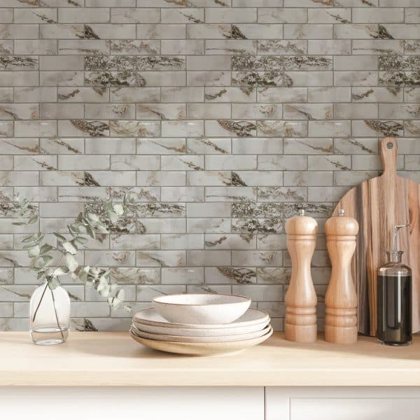 White And Beige Marble-Look Brick Tile Backsplash With Stacked Bowls, Salt And Pepper Shakers, And A Wooden Cutting Board On A Light Wood Counter.