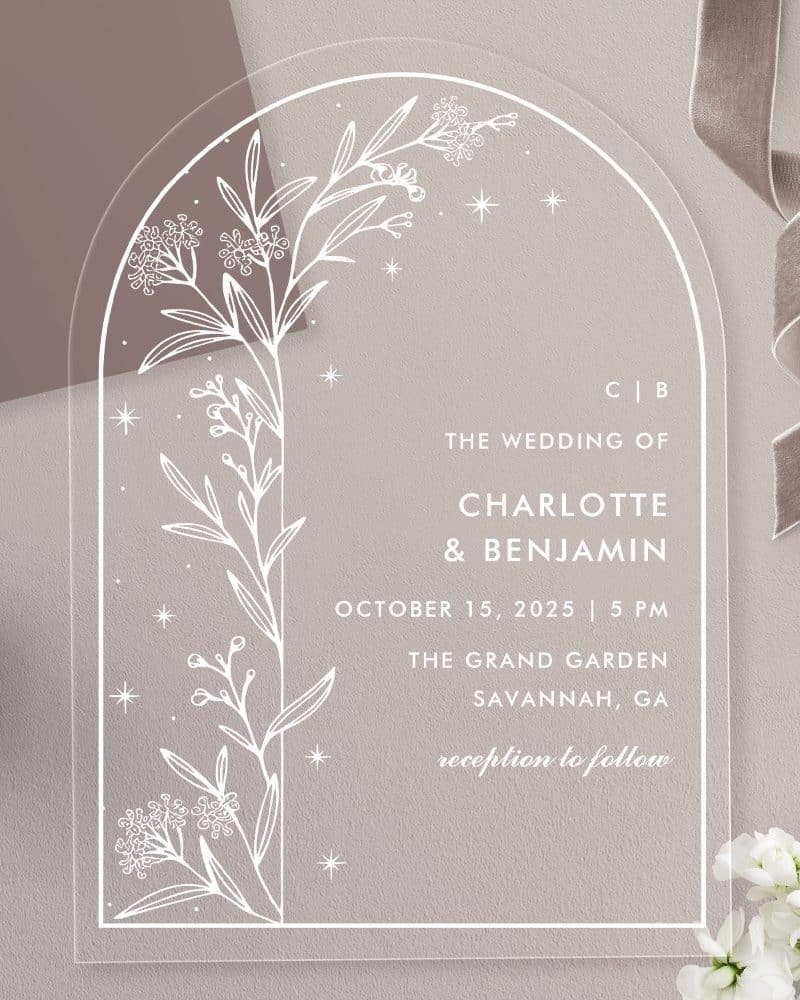 Clear acrylic wedding invitation with an arched top, featuring a line drawing of floral branches and stars. The invitation announces Charlotte and Benjamin's wedding.